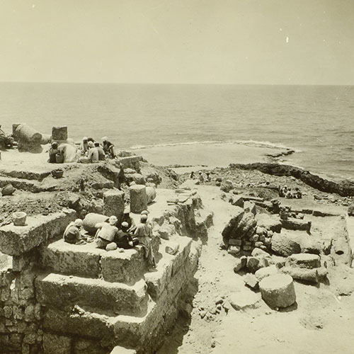 مشهد جغرافي عام لصخور القرية المحاذية للشاطئ وعليها مجموعة من الصيّادين