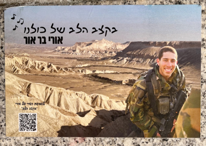 מדבקת הנצחה לאורי בר־אור ז"ל וקישור ליצירה שלו "בקצב הלב", מתוך "קירות 7.10", צולם על ידי יעל נצר.